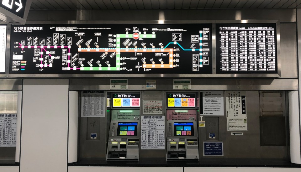 Photo of two subway ticket machines with complex maps above them
